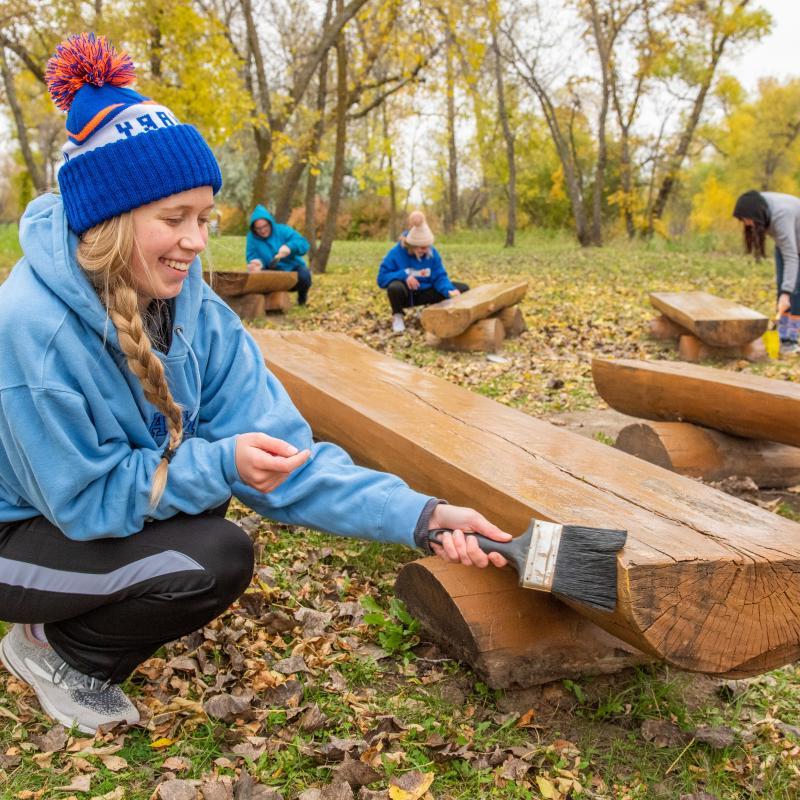 Female student painting a bench during day of service.